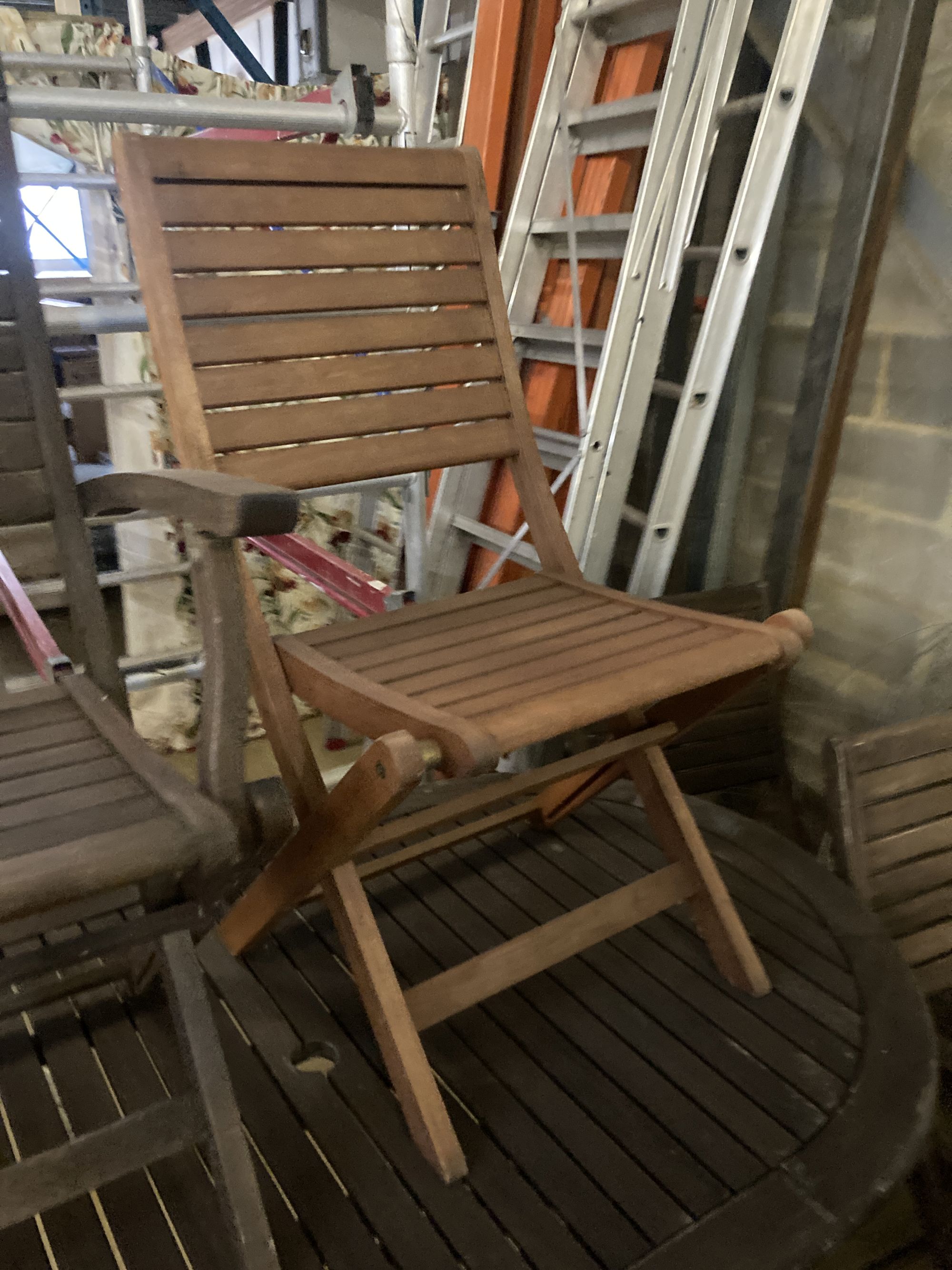 A weathered teak garden table and six teak folding chairs (two with arms)